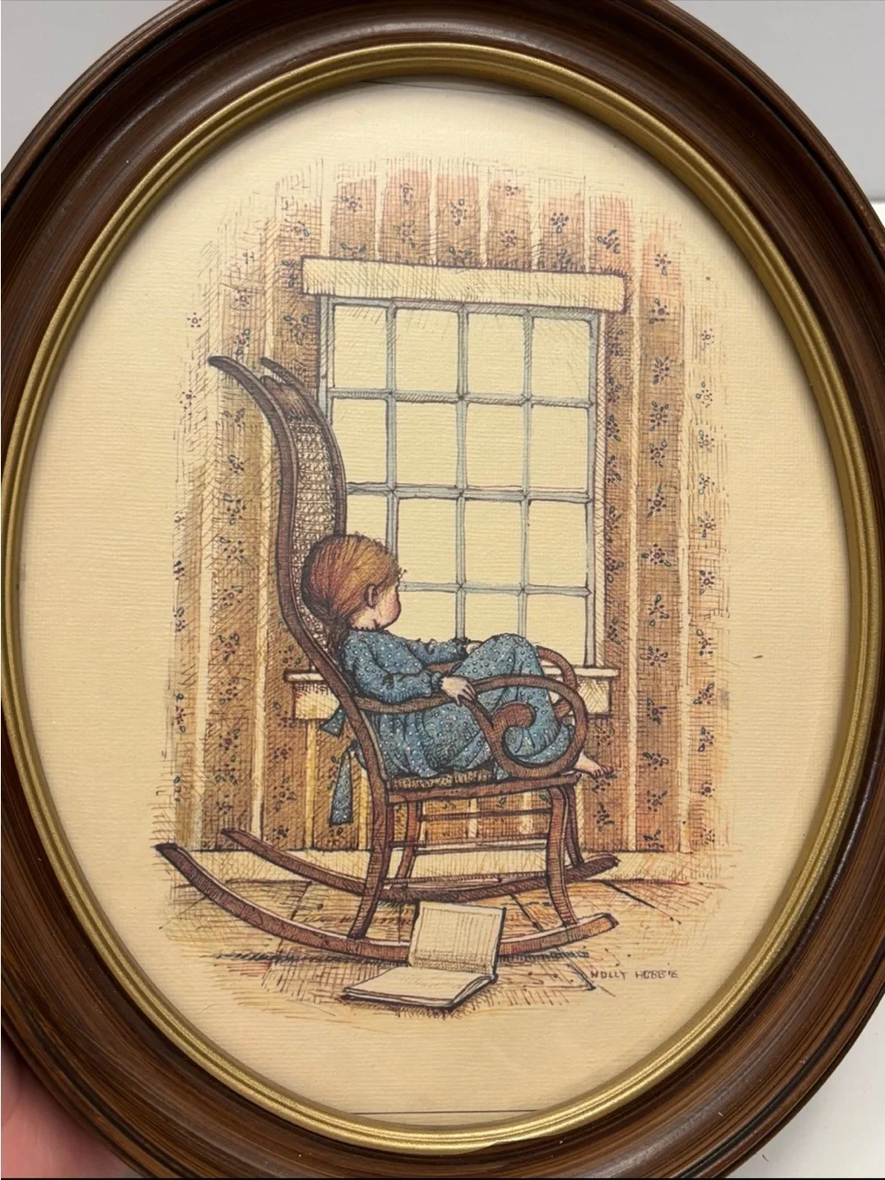 Vintage oval framed wall art piece featuring a girl in a rocking chair by a wind